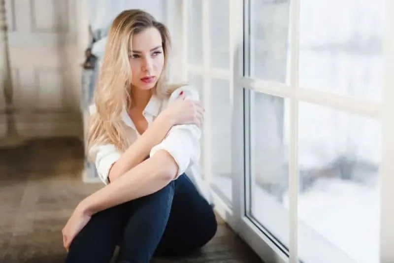 traurige Frau sitzt am Fenster