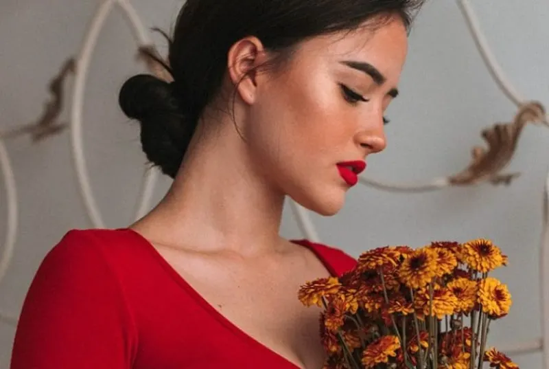 Ein Mädchen in einem roten Kleid hält Blumen in den Händen