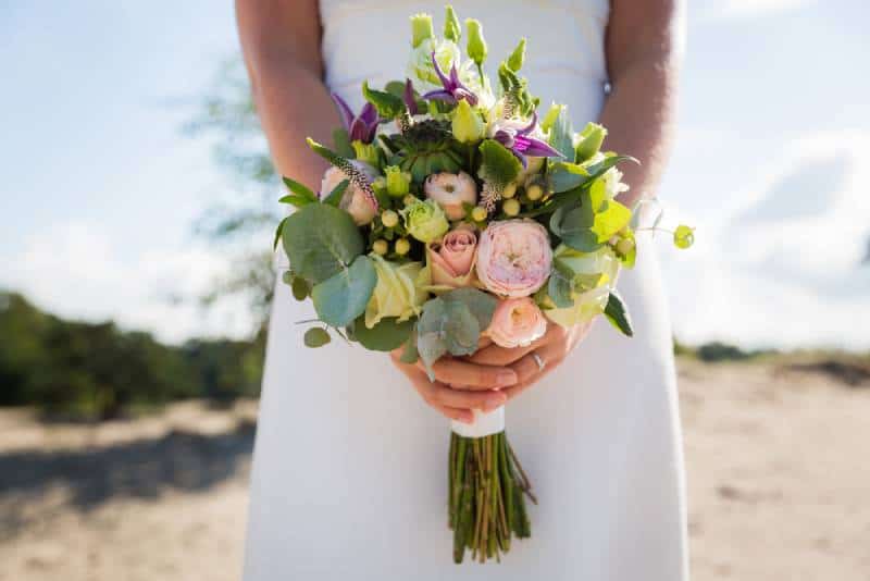 Braut hält ihren Hochzeitsstrauß mit bunten Blumen