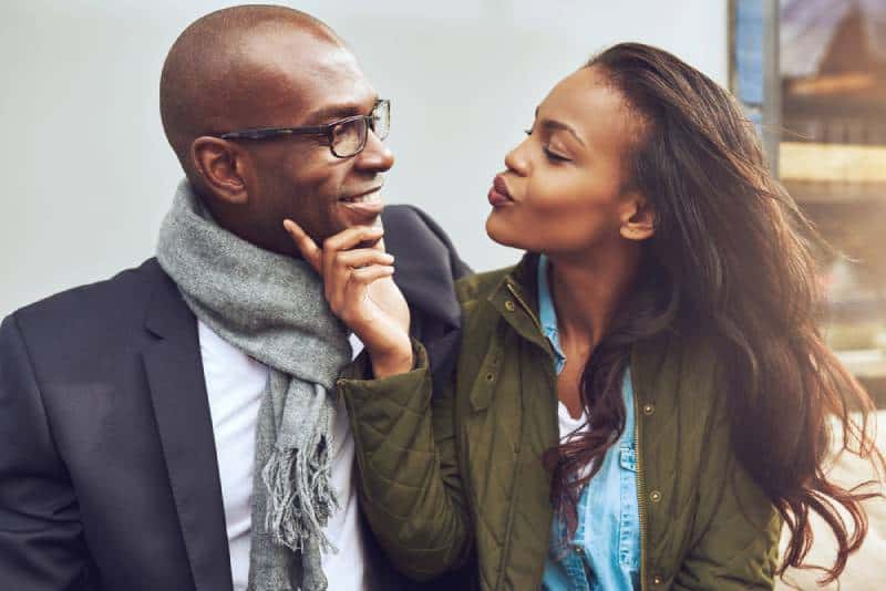 Das flirtende junge Mädchen berührt den Mann im Gesicht