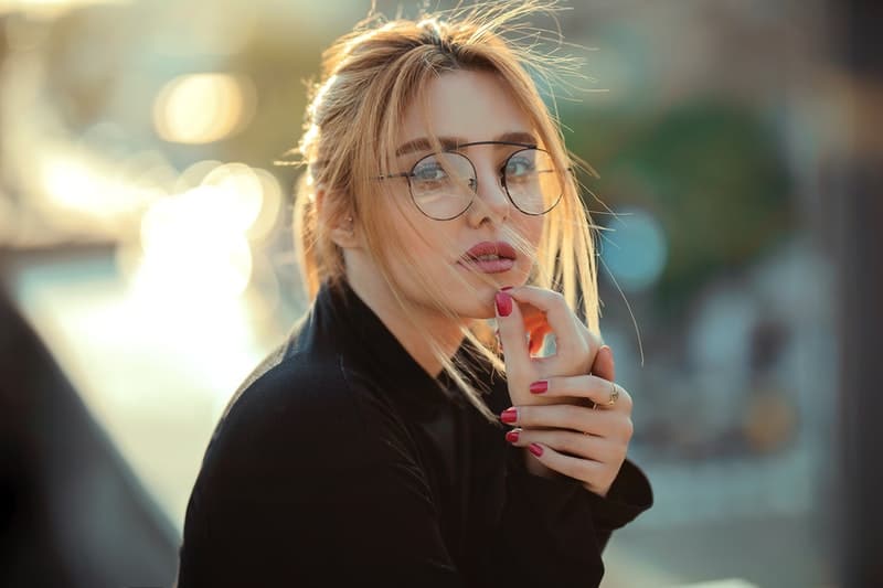 Die Frau mit der Brille berührt ihr Kinn
