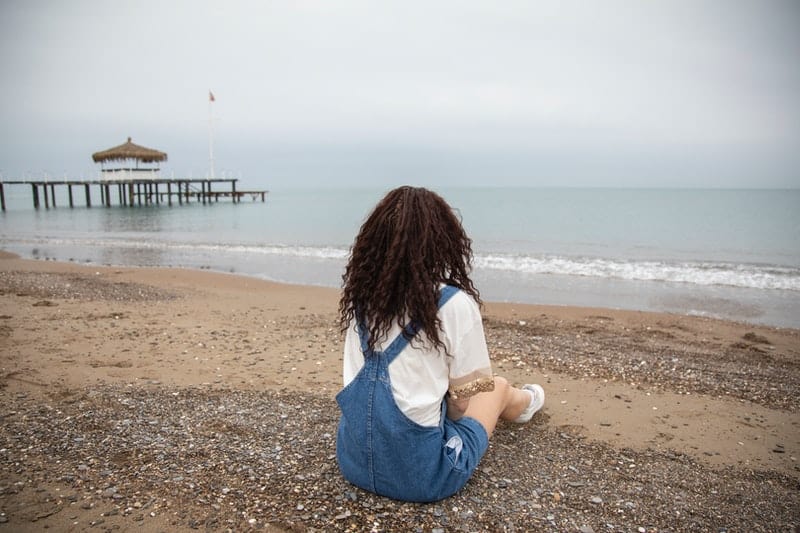 Die Frau sitzt am Strand