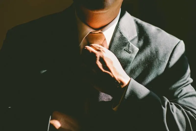 Ein Mann in einem schwarzen Anzug lockert seine Krawatte