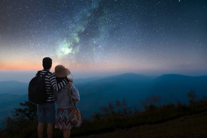 Ein Paar schaut in einer romantischen Nacht auf die Sterne am Himmel und die Milchstraße