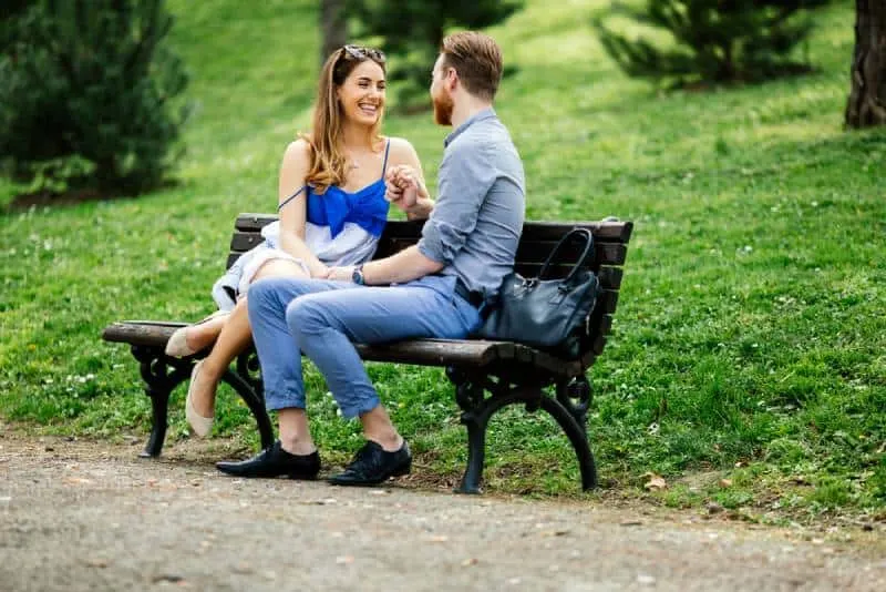 Ein romantisches Paar, das spricht und auf einer Parkbank sitzt