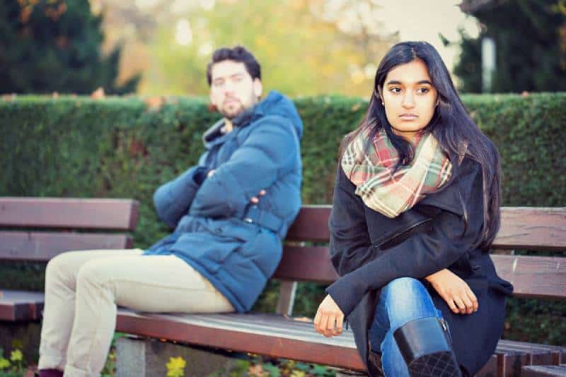 Ein verärgertes Paar, das auf einer Parkbank sitzt