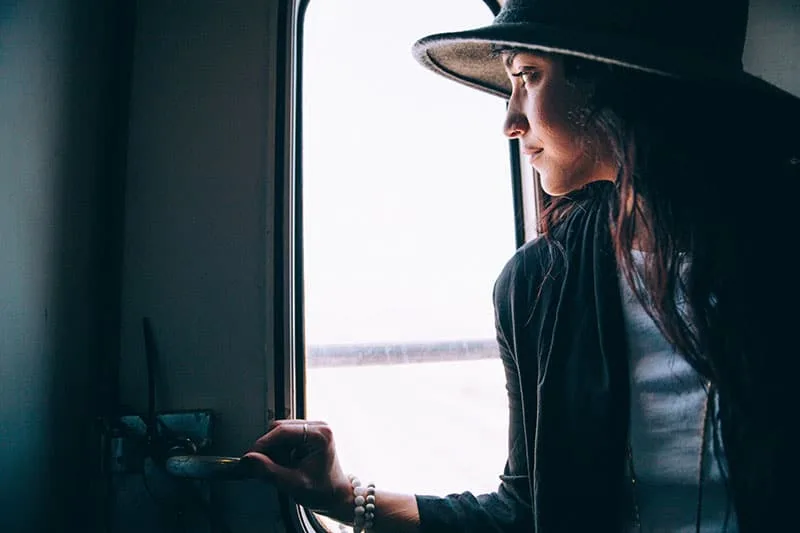 Eine Frau mit Hut schaut aus dem Fenster