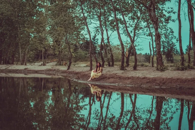 Eine Frau sitzt vor einem See