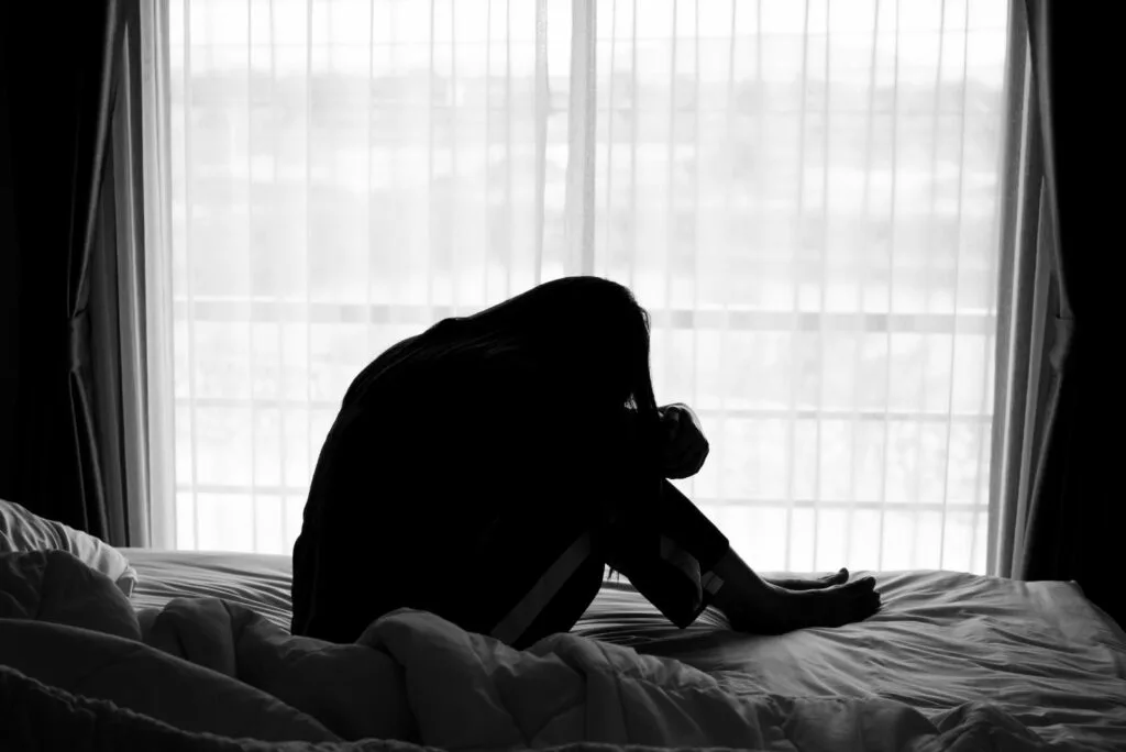 Enttaeuschtes Maedchen sitzt auf dem Bett