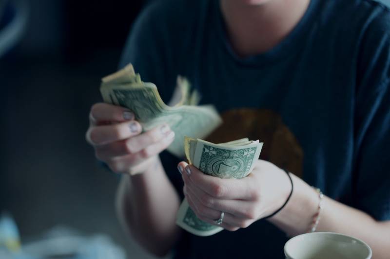 Fokusfotografie der Person, die Dollarbanknoten zählt