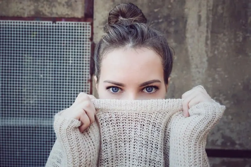 Frau bedeckt ihr Gesicht mit einem Pullover