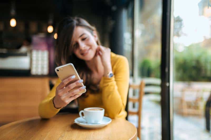 Frau, die auf ihrem Telefon im Café tippt