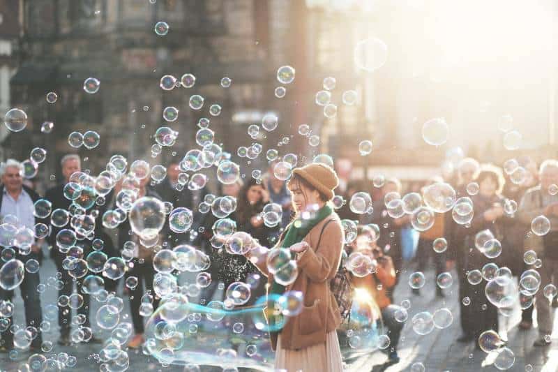 Frau, die draußen durch Blasen während des Tages umgeben steht
