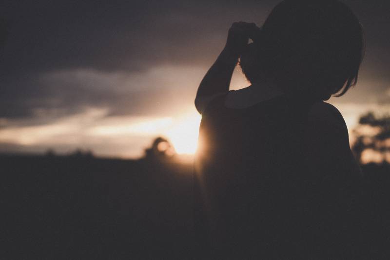 Frau, die draußen bei Sonnenuntergang steht