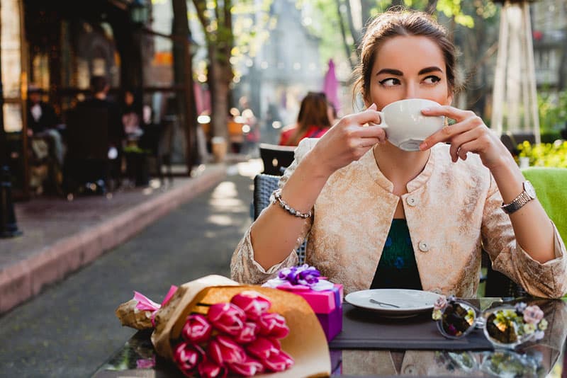 Frau, die draußen im Café Tee trinkt