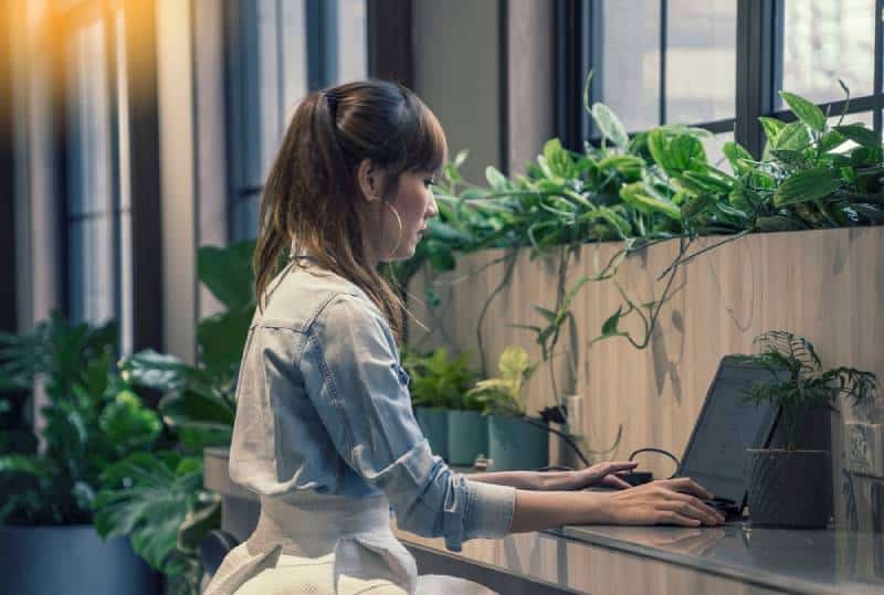 Frau, die eine Anwendung mit Laptop im modernen Büro ausfüllt
