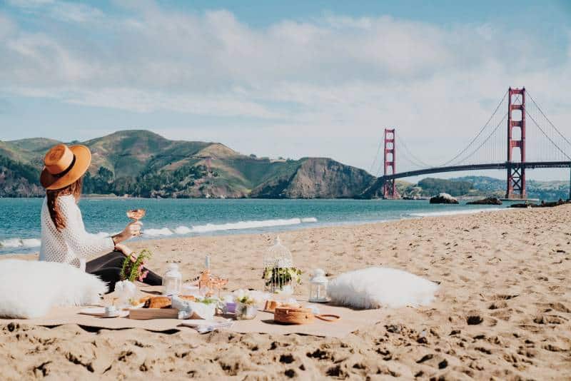 Frau, die nahe Küste sitzt, während sie Golden Gate, San Francisco betrachtet