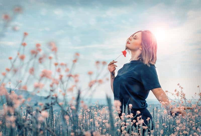 Frau, die rote Blume draußen hält