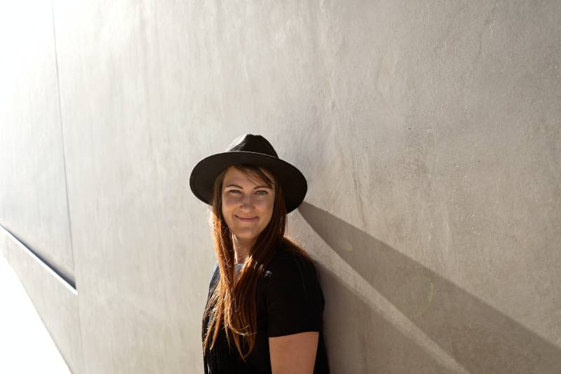 Frau, die sich auf weiße Betonwand stützt