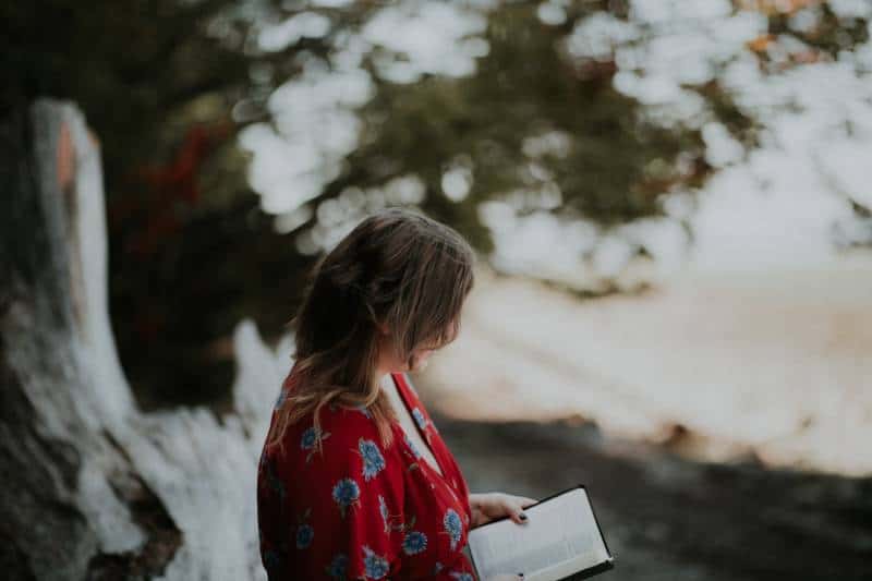 Frau hält Buch am Strand