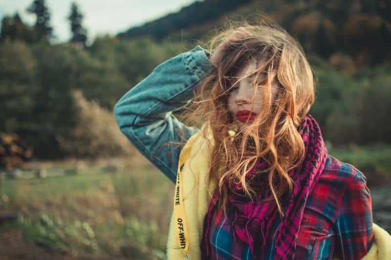 Frau hält ihre Hand auf Haar gegen Wind