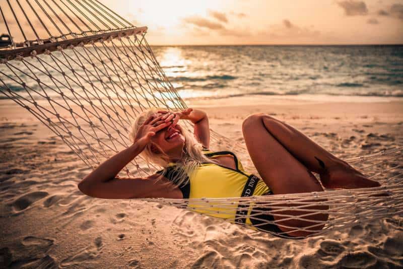 Frau im gelben Bikini, der tagsüber auf Hängematte am Strand liegt