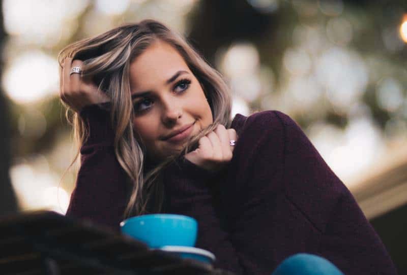 Frau in lila Langarm Top hält ihre Haare