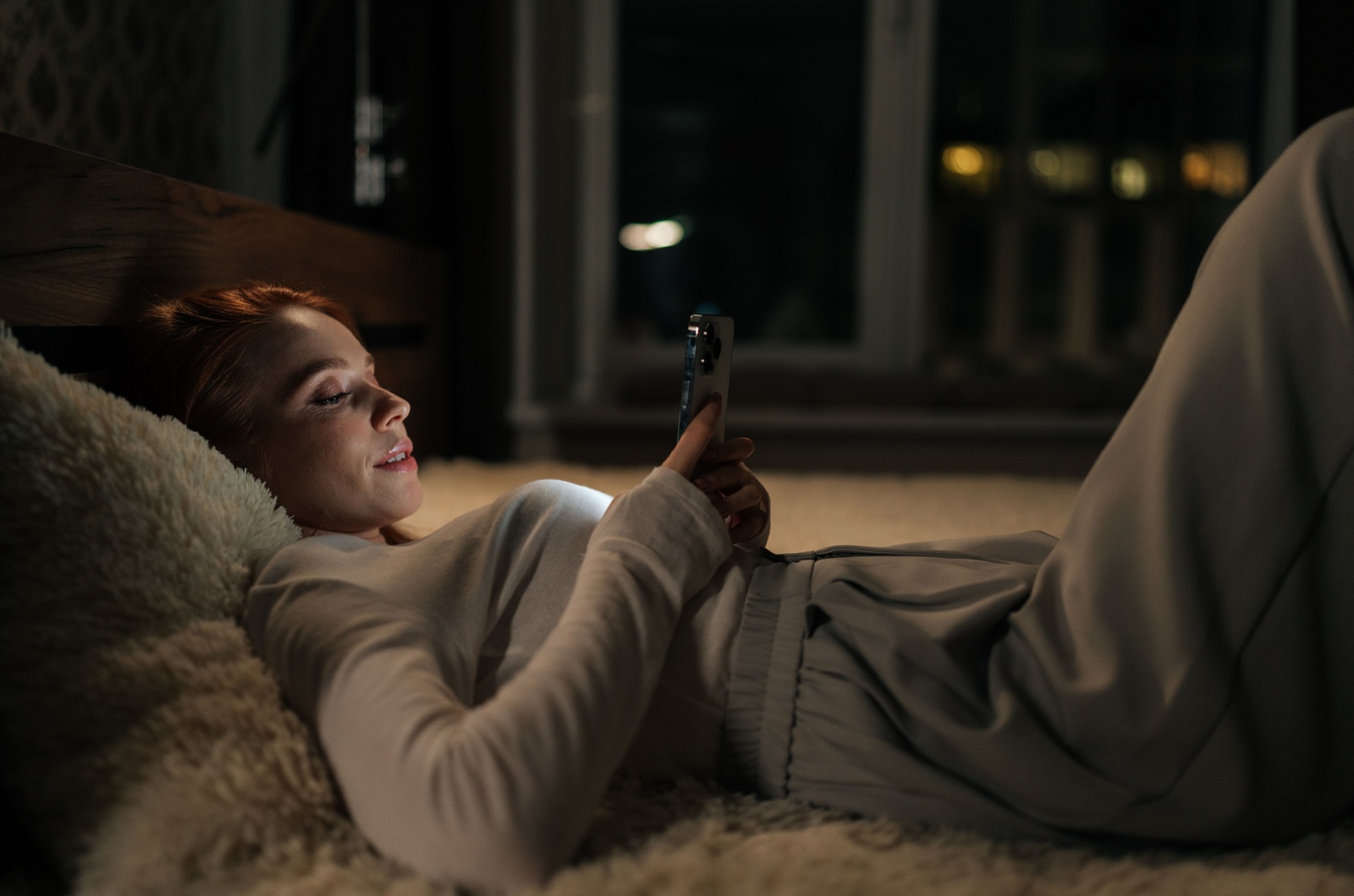 Frau liegt im Bett und tippt