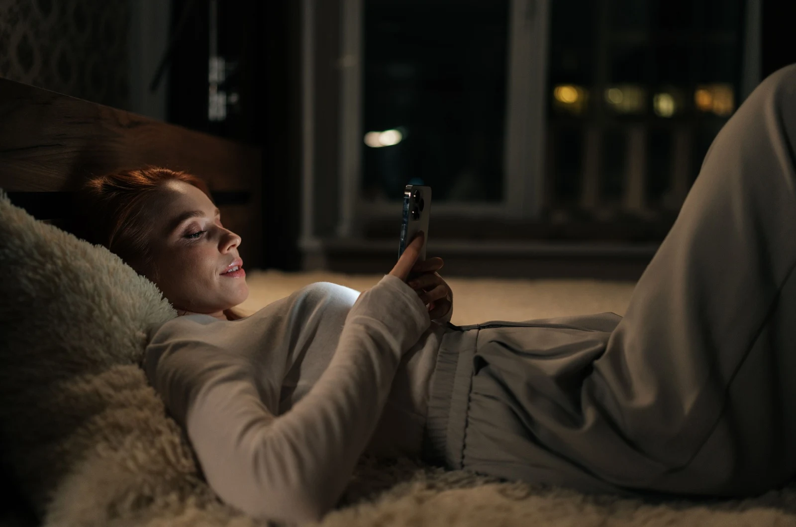 Frau liegt im Bett und tippt