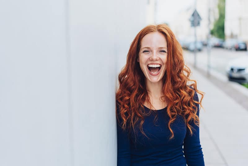 Frau mit roten Haaren lacht laut