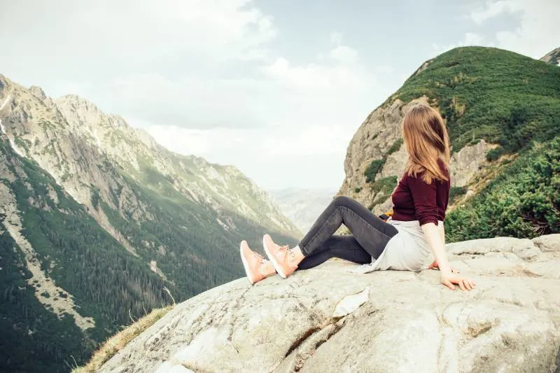 Frau sitzt auf Berggipfel