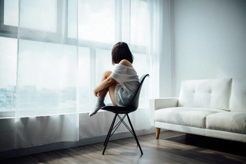 Frau sitzt auf schwarzem Stuhl zu Hause