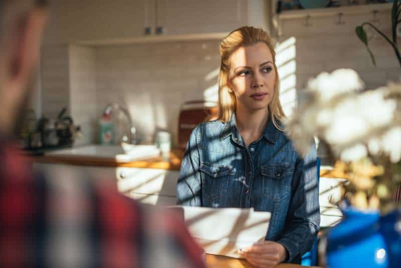 Frau sitzt in der Küche und denkt nach