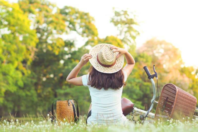 Frau sitzt in der Nähe ihres Fahrrads im Park
