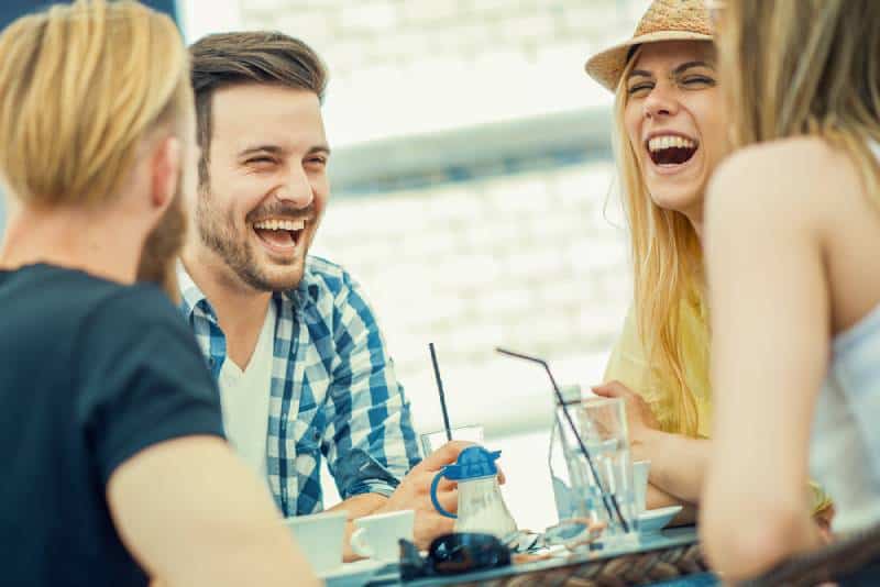 Freunde lächeln und sitzen in einem Café, trinken Kaffee und genießen zusammen