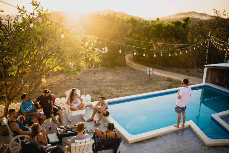Freunde sitzen auf Stühlen in der Nähe von Pool