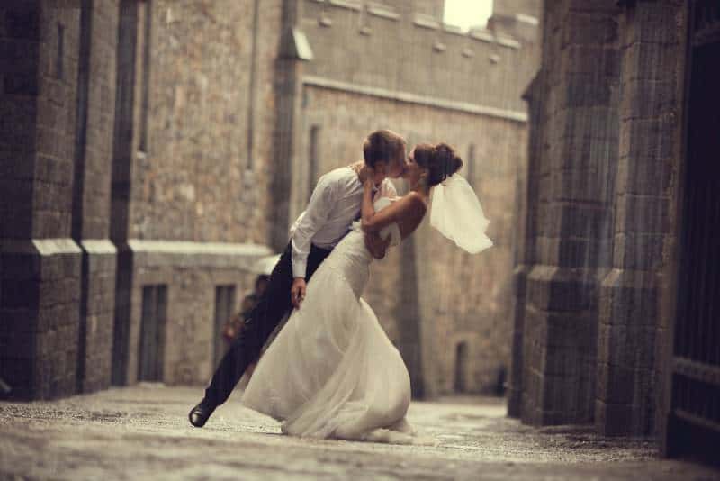 Hochzeitspaar umarmt und küsst sich am Tor