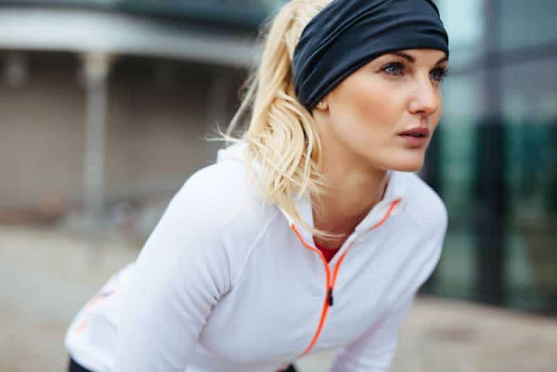 Junge Frau, die sich in Sportausrüstung beugt