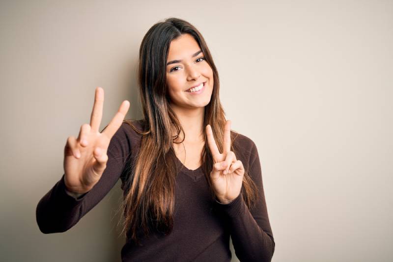 Junges schönes Mädchen, das lässigen Pullover trägt, der über lokalisiertem weißem Hintergrund steht