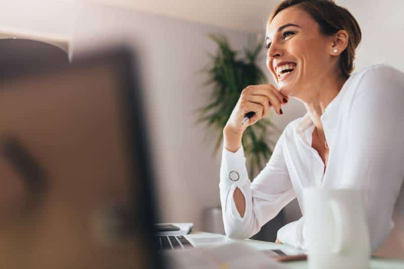 Lächelnde Frau, die an ihrem Schreibtisch im Büro sitzt
