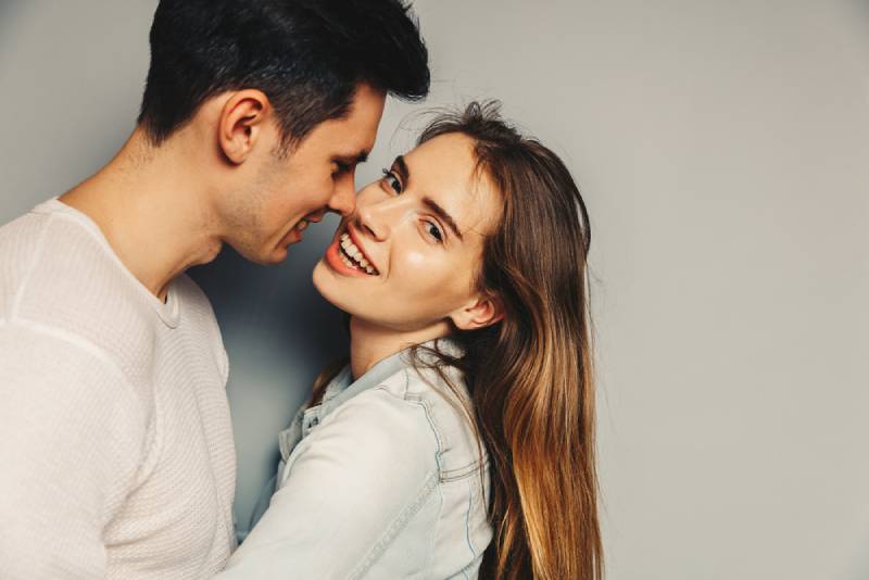 Mann küsst lächelnde Frau auf Wange