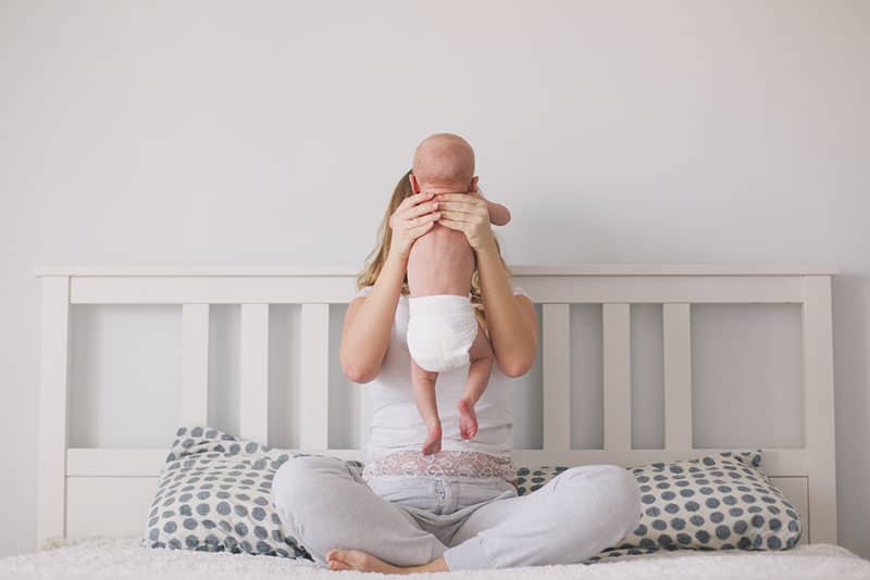 Mutter hält ihr Baby auf dem Bett