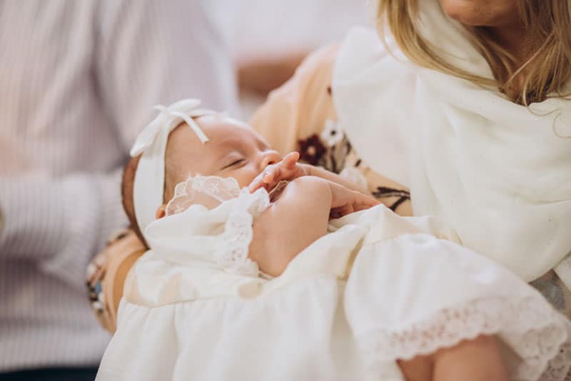 Mutter hält ihr Baby zur Taufe