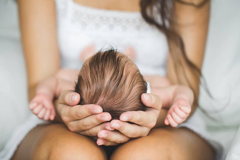 Mutter hält ihr neugeborenes Baby in Händen