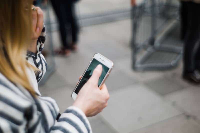 Mädchen, das draußen ein Telefon tippt
