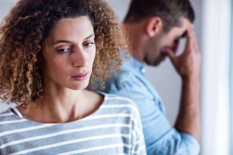Nahaufnahme der unglücklichen Frau, Mann, der an Wand im Hintergrund lehnt