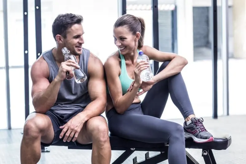 Paar Trinkwasser und sitzen im Fitnessstudio