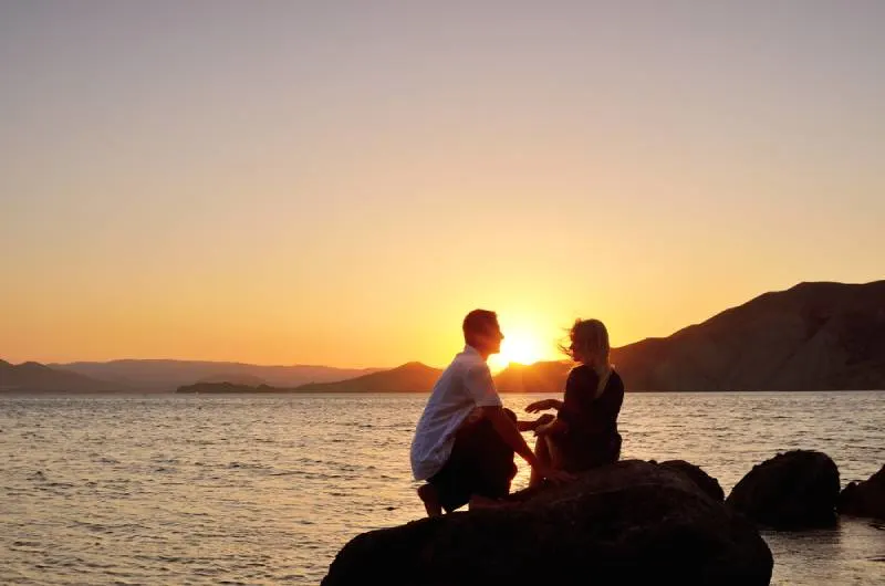 Paar sitzt am Meer auf Sonnenuntergang
