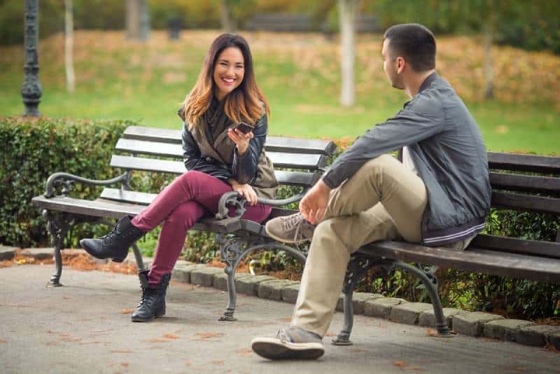 Paar sitzt auf einer Bank in einem Park und redet
