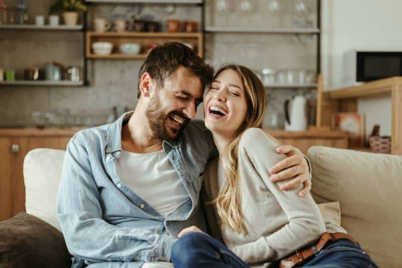 Paar umarmt und lächelt im Wohnzimmer